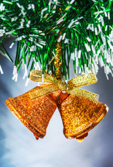 A golden bell-shaped ornament hanging on a green Christmas tree.
