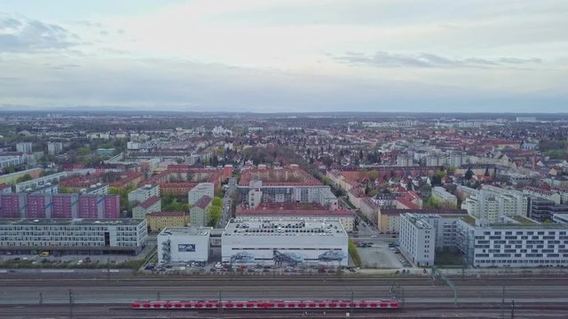 Blick &uuml;ber M&uuml;nchen mit Bergen im Hintergrund und einem fahrendem Zug im Vordergrund
