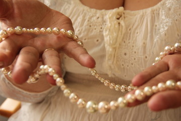 female hands hold pearl beads. On her hands scars from burns