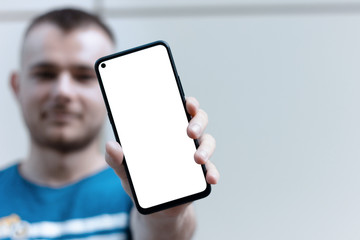 A young man showing his smartphone with white screen. Smartphone blank screen with frontal camera...