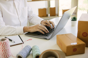 Entrepreneurs are working on taking orders of customers products by typing information tpying keyboard laptop computer in office room.