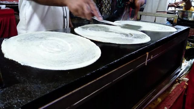 Chef making three dosa in a row. Dosa Indian food chef hand while cooking Dosa.