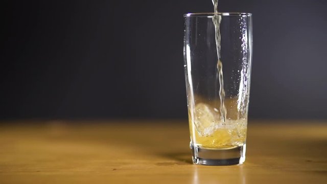 Filling up a glass of beer, slowmotion, dark background