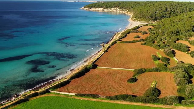 Drone flying and filming panorama over Binigaus beach and fields  in Menorca Island, Spain