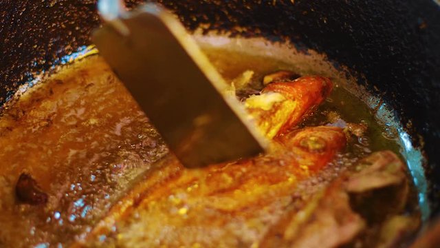 Red snapper fish being fried in oil in deep pan