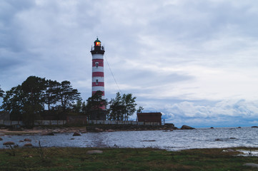 Lighthouse shines near the shore at sunset