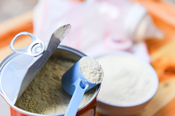 Milk powder in spoon on can and wooden table baby milk bottle - obrazy, fototapety, plakaty