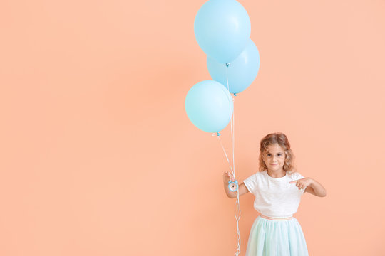 Little girl with balloons and clock on color background