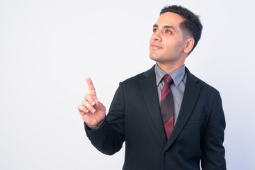 Portrait of handsome Persian businessman in suit thinking and pointing up