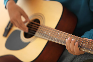 Little boy playing guitar at home, closeup