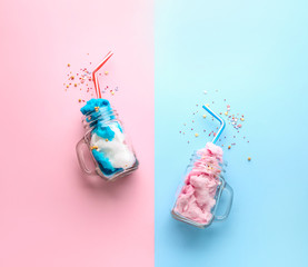 Jars with tasty cotton candy and sprinkles on color background
