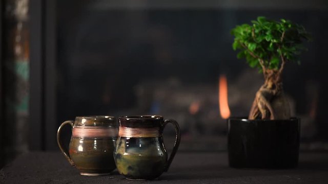 Two pottery mugs in front of a gas fireplace