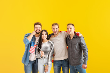 Fototapeta premium Happy young friends with national flags of USA on color background
