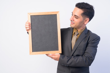 Portrait of handsome Persian businessman in suit holding blackboard