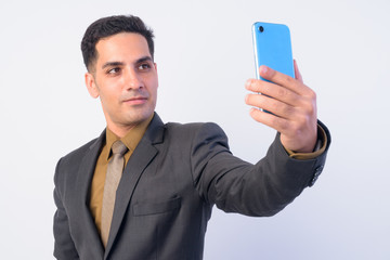 Portrait of handsome Persian businessman in suit taking selfie