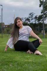 Fototapeta premium LATIN WOMAN WITH BLACK PANTS SITTING ON THE LAWN
