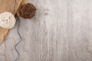 twine and two decorative balls, burlap and coffee mug on light gray wooden background.