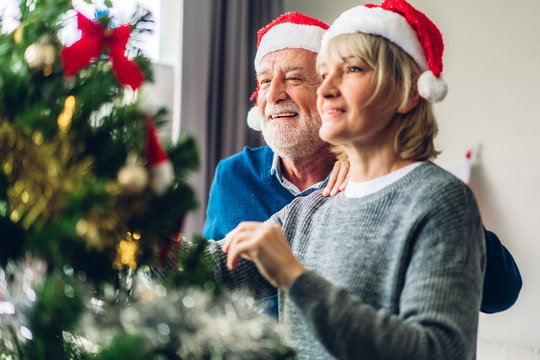 Romantic sweet senior couple relaxing  decorating christmas tree and smiling while celebrating new year eve and enjoying spending time together in christmas time at home