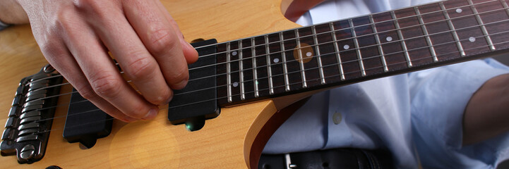 Male arms playing classic shape electric guitar