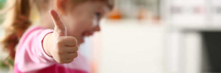 Kleine Mädchen zeigen mit ihrem Arm genehmigen oder OK-Zeichen