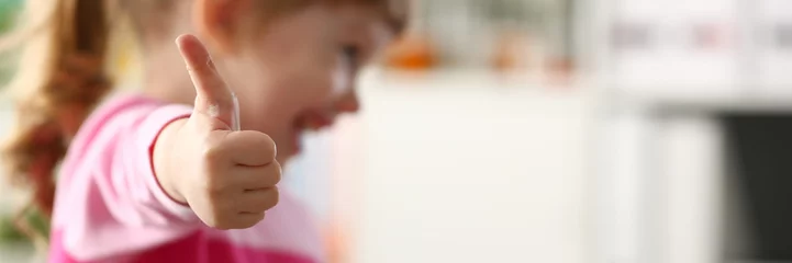 Foto op Plexiglas Kinderopvang Klein meisje toont goedkeuren of OK-teken met haar arm