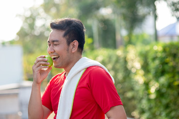 Happy Asian sport man with green apple in his hand outdoor.