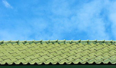 Old weathered asian green roof with blue sky as background.