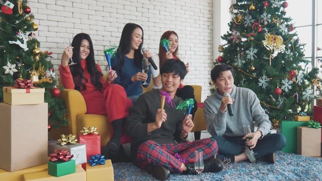 Happy party of young Asian with drink wine and sing a song at home in celebrate Christmas festival. Celebration of new year at house. Merry Christmas and happy holidays of gang teen Thai.