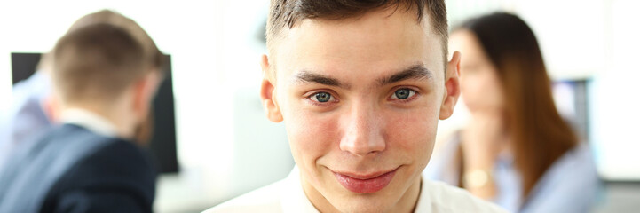 Young smiling clerk in shirt and tie looking in camera