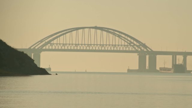 View of the bridge over the river with passing ships. Shot. Timelapse. Movement of shipping ships on the river in the early morning