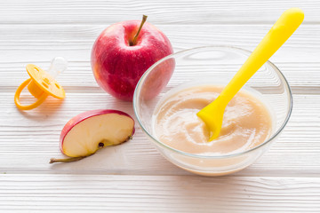 Apple puree for feed babies on white wooden background