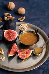 figs with a spoon of honey in a copper plate on a purple background