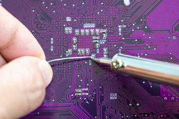 Technicians are using a soldering iron for repairing electronic of the computer circuit board...