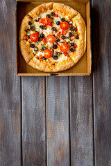 Pizza delivery. Italian food in box on dark wooden background top view space for text