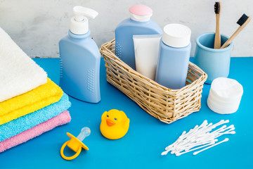 Baby bathroom cosmetics near pacifier and rubber duck on blue background