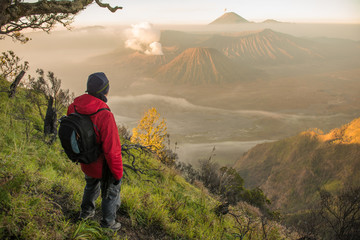 Back view of tourist standing on the hill and looking to the beautiful sunrise of Bromo Tengger Semeru National Park in East Java, Indonesia. 