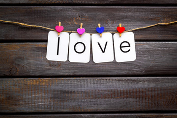Cute heart icons garland with text love on dark wooden background top view copy space