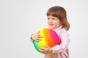 Fototapeta na wymiar Adoption and parenting by homosexual couple and families concept. Children against homophobia.Sweet two year old little baby girl with a happy face smiles and hugs a large ball painted LGBT rainbow.