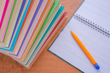 Exercise book and pen lie on the table with books