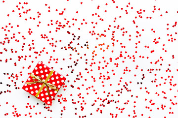 Valentine's Day concept - a gift box over scattered heart shaped confetti background.