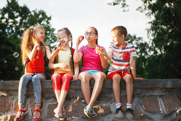 Teenagers sit on a wall outside.