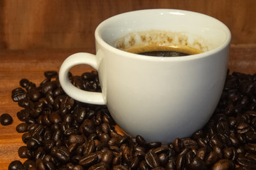 Coffee mugs and coffee beans resting on a brown wooden table.