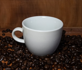 Coffee mugs and coffee beans resting on a brown wooden table.