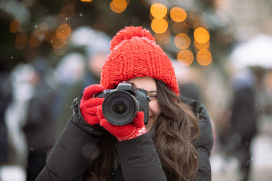 woman photographer with professional camera shooting outdoors at winter time