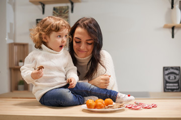 Mom and daughter in the kitchen celebrate Christmas with tangerines or New Year. Care and love, warmth. Horizontal frame.