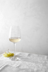 White wine in a glass and a bunch of grapes on the table.