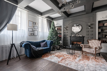 Christmas morning. Classic apartments with study and library a fireplace, decorated tree, sofa, large windows and chandelier.