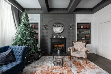 Christmas morning. Classic apartments with study and library a fireplace, decorated tree, sofa, large windows and chandelier.