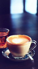 Hot coffee with beautiful latte art on wooden coffee table, vintage color   tone process and selective focus for business food and drink background