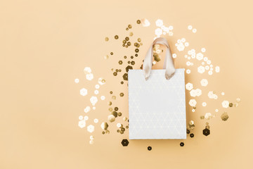 Paper shopping bag and trendy hexagonal sparkles on beige background. Holiday sale concept in...